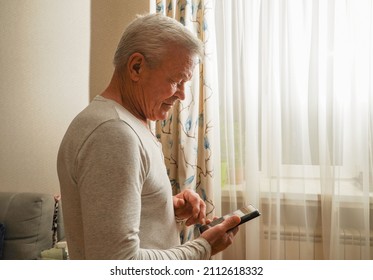   Retired Male Chatting With Friends In Social Media, Typing On Smartphone. Happy Senior Man Using Phone At Home.                              