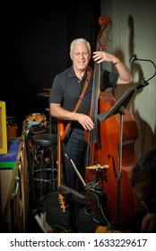 Retired Man With Silver Gray Hair Playing Stand Up Bass Back Stage At The Theater