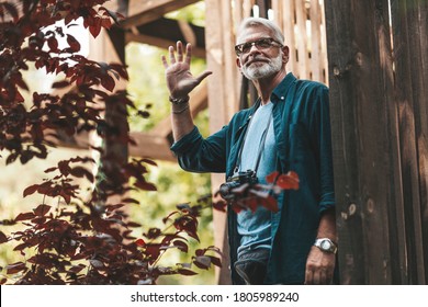 Retired Neighbor With A Beard Greets And Smiles On The Terrace Of The House. Support And Care For Old People. Thanks To The Volunteers For Their Help.