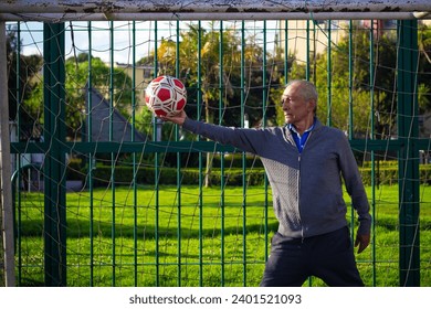 retired older man being a goalkeeper on a soccer field in a park - Powered by Shutterstock