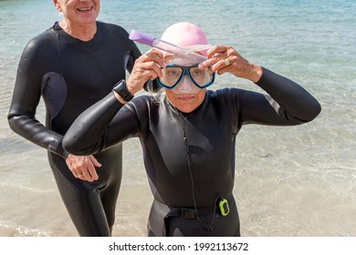 Retired Older Woman Dressed In A Wetsuit Putting On Snorkeling Goggles