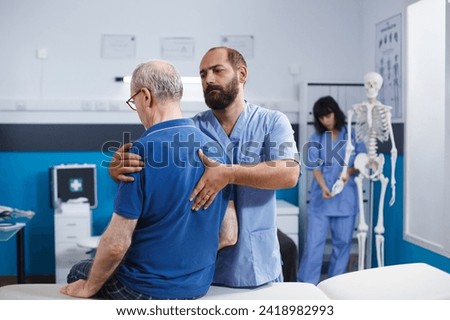 Retired patient receives chiropractic care for back discomfort in order to heal physically. Nurse aids old man in recovering from spine injury and providing orthopedic massage for physical therapy.