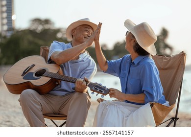 retired, retirement, couple, senior, elderly, beach, recreation, insurance, planning, vacation. A man and woman are playing guitar on the beach. Scene is happy and friendly. - Powered by Shutterstock