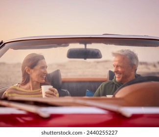 Retired Senior Couple In Classic Sports Car With Hot Drink At Beach Watching Sunrise - Powered by Shutterstock