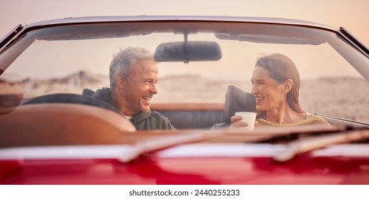 Retired Senior Couple In Classic Sports Car With Hot Drink At Beach Watching Sunrise - Powered by Shutterstock