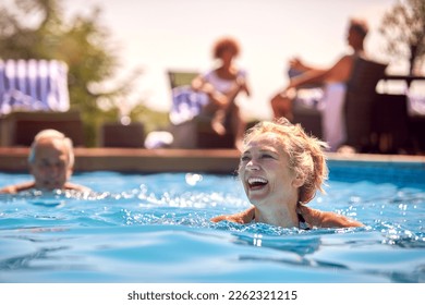 Retired Senior Couple Relaxing In Swimming Pool On Summer Vacation - Powered by Shutterstock