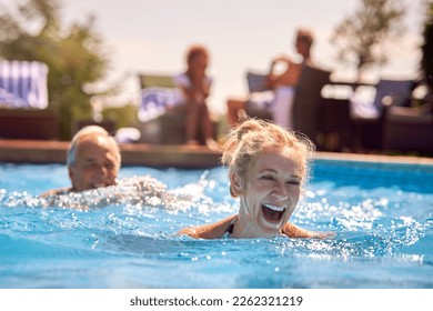 Retired Senior Couple Relaxing In Swimming Pool On Summer Vacation - Powered by Shutterstock