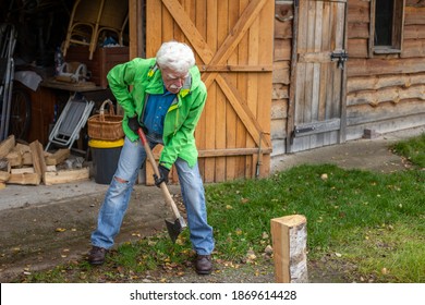 Retired senior man holding the heavy axe. Axe in lumberjack hands chopping or cutting wood trunks. - Powered by Shutterstock