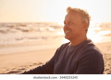 Retired Senior Man On Vacation Sitting On Beach Shoreline Watching Sunrise - Powered by Shutterstock