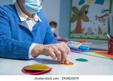 Retired Senior Woman Attending Class In Community Center, Wearing Face Mask. Making Memory Exercises With Hands. 