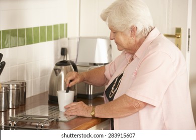 Retired Senior Woman In Kitchen Making Hot Drink