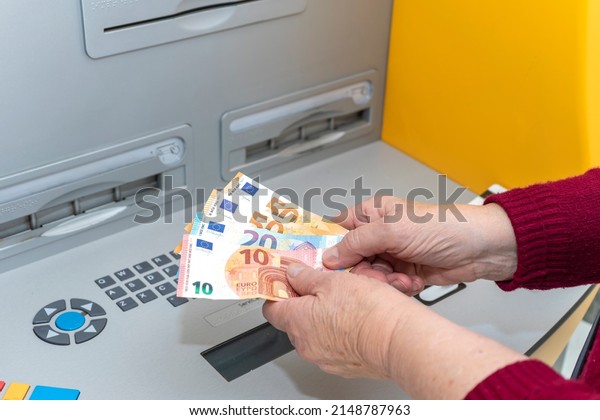 RETIRED SENIOR WOMAN WITHDRAWING MONEY FROM\
AN ATM. DIGITAL DIVIDE AMONG THE\
ELDERLY.