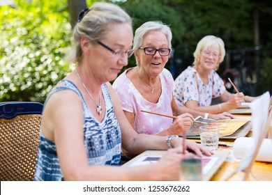 Retired senior women painting together outdoors as group recreational and creative activity during summer. - Powered by Shutterstock