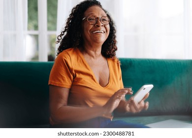 Retired woman using her smartphone to stay connected with her loved ones. Senior woman using mobile technology to make phone calls, send text messages, access social media, and browse the internet.