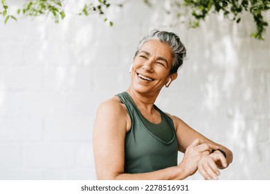 Retired woman using her smartwatch to track her fitness progress and stay connected while enjoying an outdoor workout. Happy senior woman taking advantage of technology to stay active and healthy. - Powered by Shutterstock