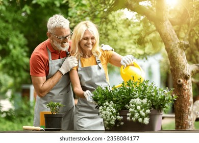 Retirement Activities. Happy Senior Spouses Gardening Together On Backyard, Smiling Mature Couple Watering Potted Flowers, Cheerful Older Man And Woman In Aprons Enjoying Planting, Copy Space - Powered by Shutterstock