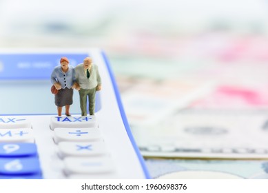 Retirement Fund, Pension Income Tax And Social Security Benefit Concept : Older American Couple Stands Near A Tax Button On A Calculator, Depicts A Single Largest Expense In Retirement E.g Pension Tax