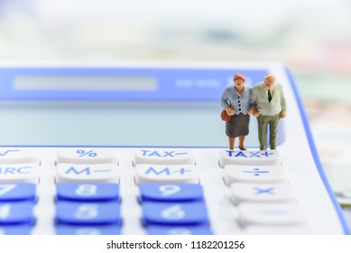 Retirement / Pension Income Tax And Social Security Benefit Concept : Older American Couple Stands Near A Tax Button On A Calculator, Depicts A Single Largest Expense In Retirement E.g Pension Tax