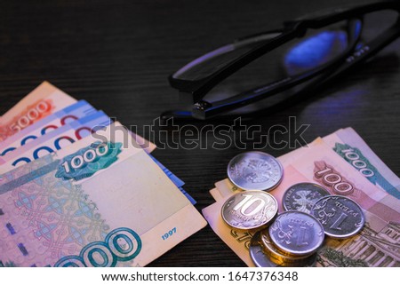 Retirement pension in Russian money. Banknotes and coins on a table close up on a black background. Indexation and benefit allowance in Russia.