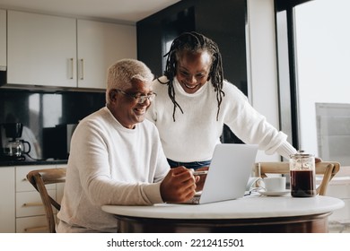 Retirement Planning At Home. Cheerful Senior Couple Smiling Happily While Looking At A Laptop Screen. Happy Mature Couple Researching Their Retirement Options Together.