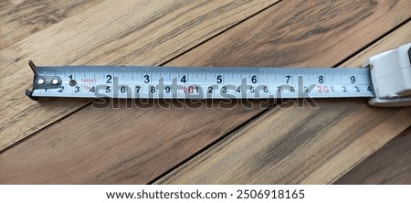 Retractable black and yellow measuring tape set at a distance of 10 cm, on a wooden background, a useful tool for measuring length, width and height. Concept of accuracy and precision