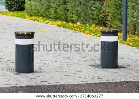 Retractable bollards providing security and traffic control on a paved sidewalk in an urban green space area