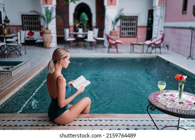 Retreat And Vacation. Beautiful Young Woman Reading Book In Spa Swimming Pool In Beautiful Moroccan Backyard.