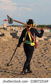 Retriever Man In Water Repellent Diving Suit Looking For Lost Metal Material During The Day With A Metal Detector On The Sandy Beach