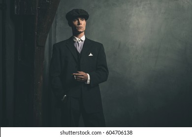 Retro 1920s english gangster standing with cigarette.