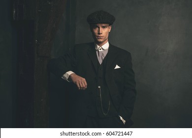 Retro 1920s english gangster wearing suit and flat cap.