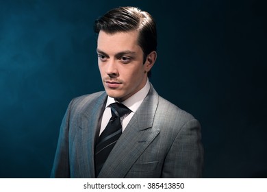 Retro 1940s Business Man In Suit And Tie Against Blue Wall.