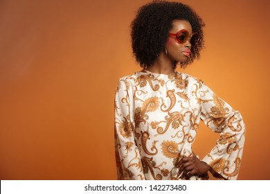 Retro 70s Fashion African Woman With Paisley Dress And Sunglasses. Brown Background.