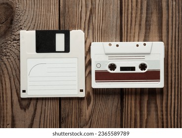 Retro 80s floppy disk and audio cassette on wooden background. Vintage technology. Top view.