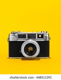 Retro analog film camera on yellow background