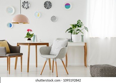 Retro armchairs, table, chandelier, ceramic wall decoration and pouf in a bright apartment interior - Shutterstock ID 1095192842