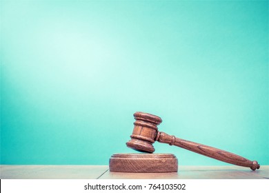 Retro auction or judge wooden gavel on table front mint green background. Vintage old style filtered photo