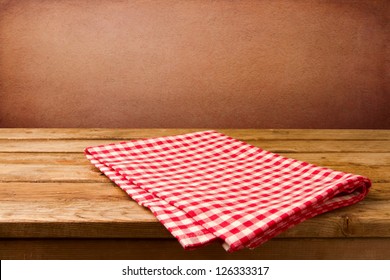 Retro background with wooden table and tablecloth over red rough wall