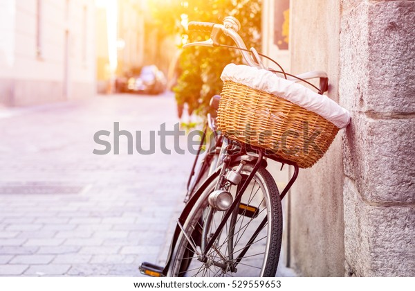 Retro\
bicycle with a basket leaning against a wall. Cycle on stone\
medieval street in historical center of Como, Italy. Retro cycle on\
blurred background with copy space area for a\
text.