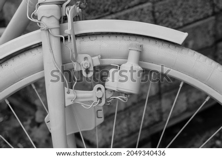Retro bicycle with the bottle dynamo device for the headlight on the front wheel. Black and white. Close up.