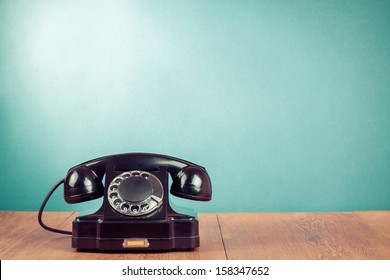 Retro black telephone on table in front mint green background