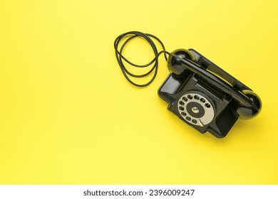 A retro black telephone on a yellow background. The old technique. A place for your text. - Shutterstock ID 2396009247