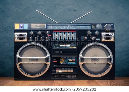 Retro boombox outdated portable black radio receiver with cassette recorder from 80s front concrete wall background. Rap, Hip Hop music concept. Vintage old style filtered photo