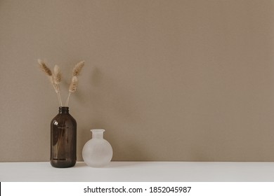 Retro Bottle With Dry Wheat / Rye Stalk Against Pastel Beige Background. Minimal Modern Interior Decoration Concept.