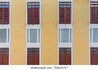 Retro building facade, pattern of red old days window on yellow wall of building.