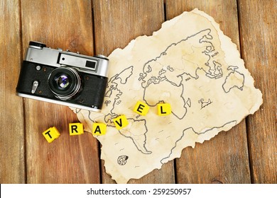 Retro Camera On World Map With Word Travel On Wooden Table Background