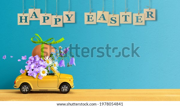 Retro car carrying an easter egg and bunch of\
flowers on the roof. Copy\
space