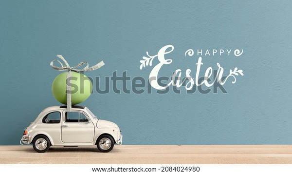 Retro car carrying an easter egg on the roof. Happy\
Easter text