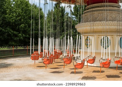 Retro carousel on chains not working with empty seats on a sunny summer day at an amusement park in Sochi