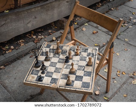 An retro chess set game consisting of a chessboard and pieces on an old chair on the street
