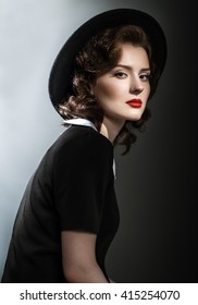 Retro Classic Portrait Of Elegant Woman In Black Hat And Dress. Red Lips. Wavy Hairstyle.